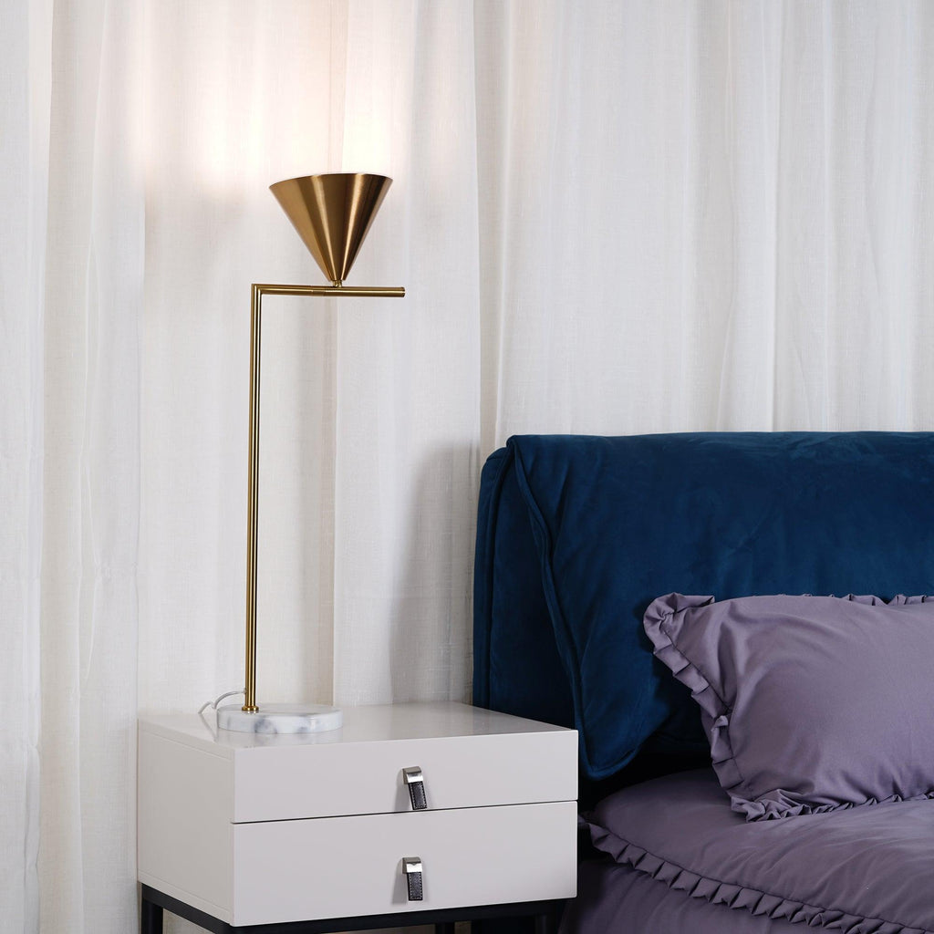 The Clérachic table lamp stands on a white nightstand with drawer pulls, its cord visible beside a navy tufted headboard.