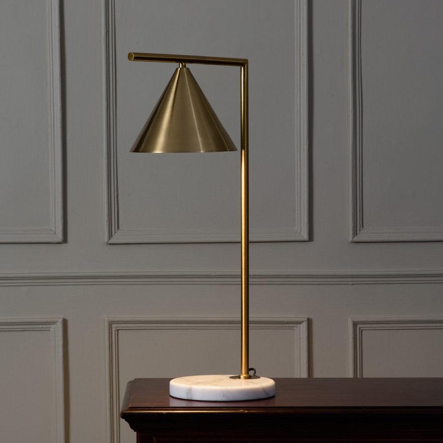 Clérachic's cone-shade table lamp stands on a dark wood console against a grey wainscoted wall, its stem catching soft side light.