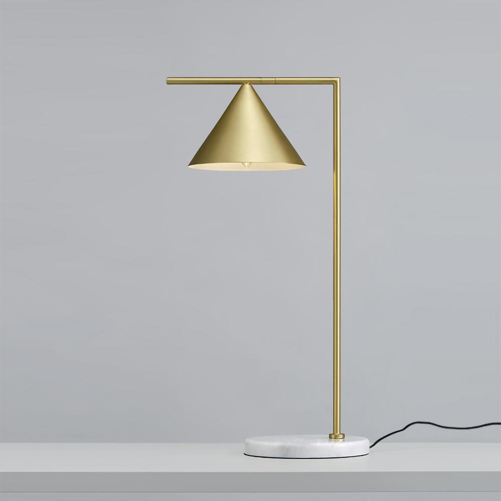 Photographed from a low angle, the Clérachic lamp's tall brass stem rises against a blue-grey backdrop, its cord trailing below.