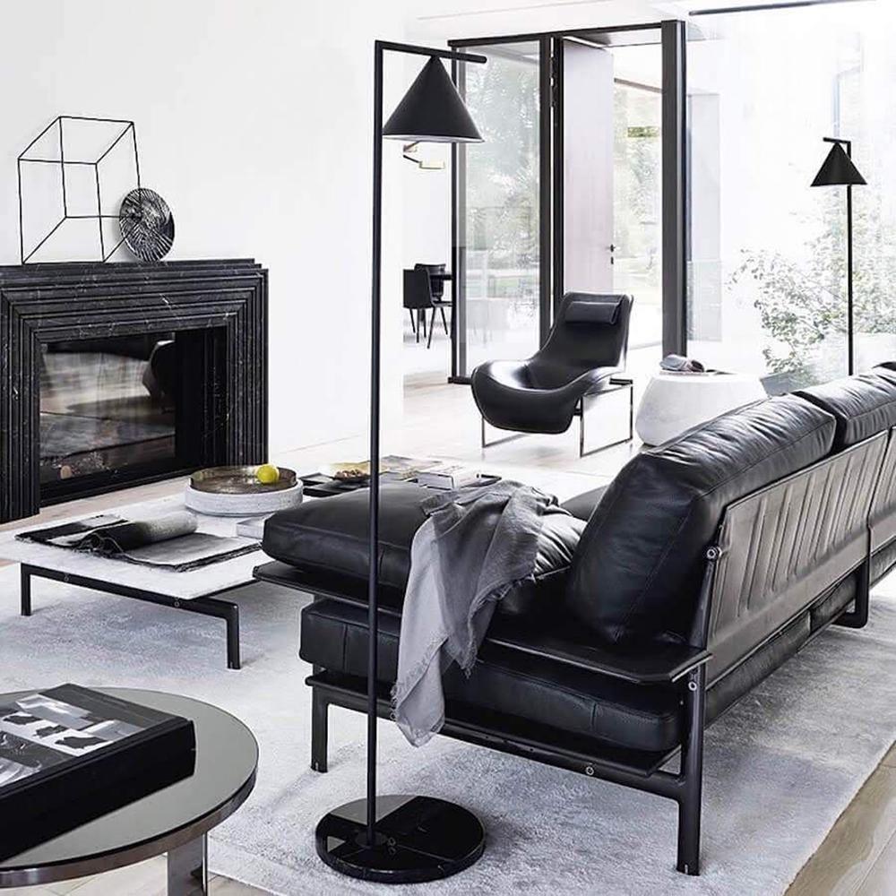 Black floor lamp with opal cone lighting a corner workspace