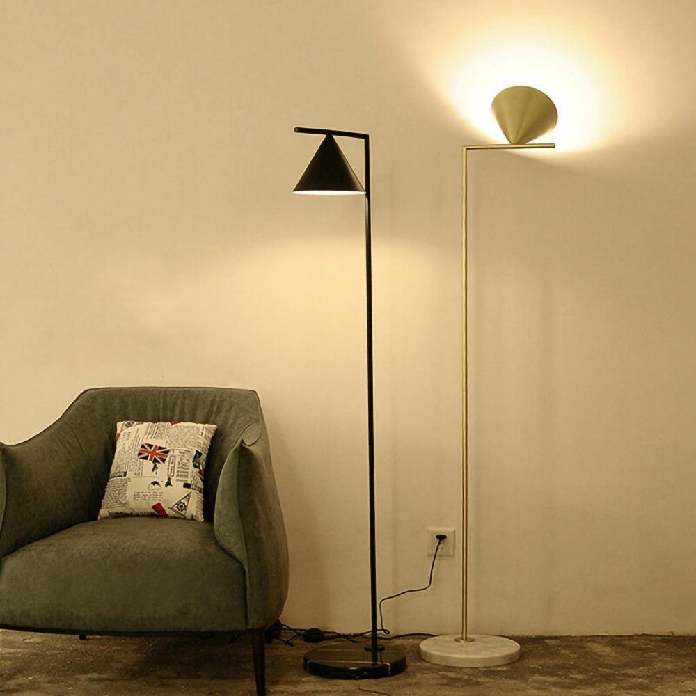 Black floor lamp with opal cone beside a minimalist armchair