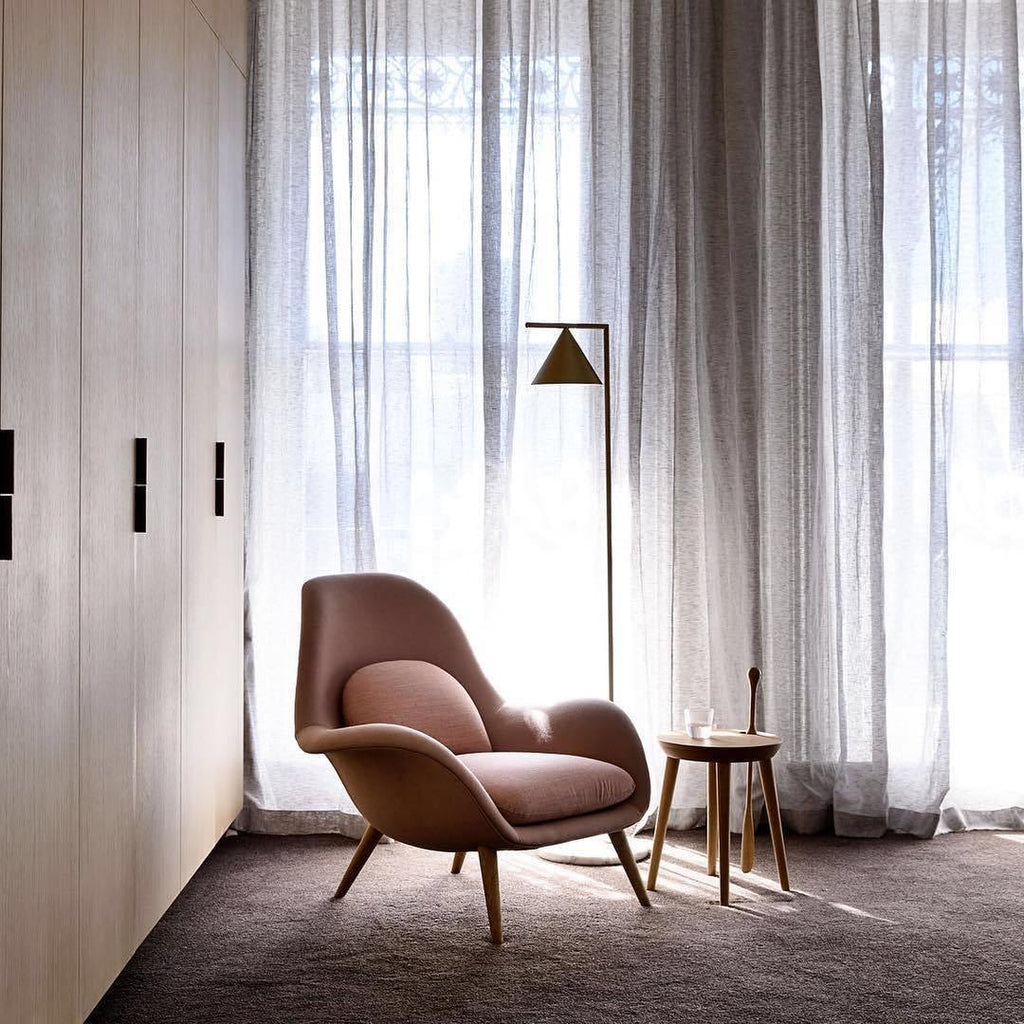 Opal cone floor lamp casting warm directed light on a wall
