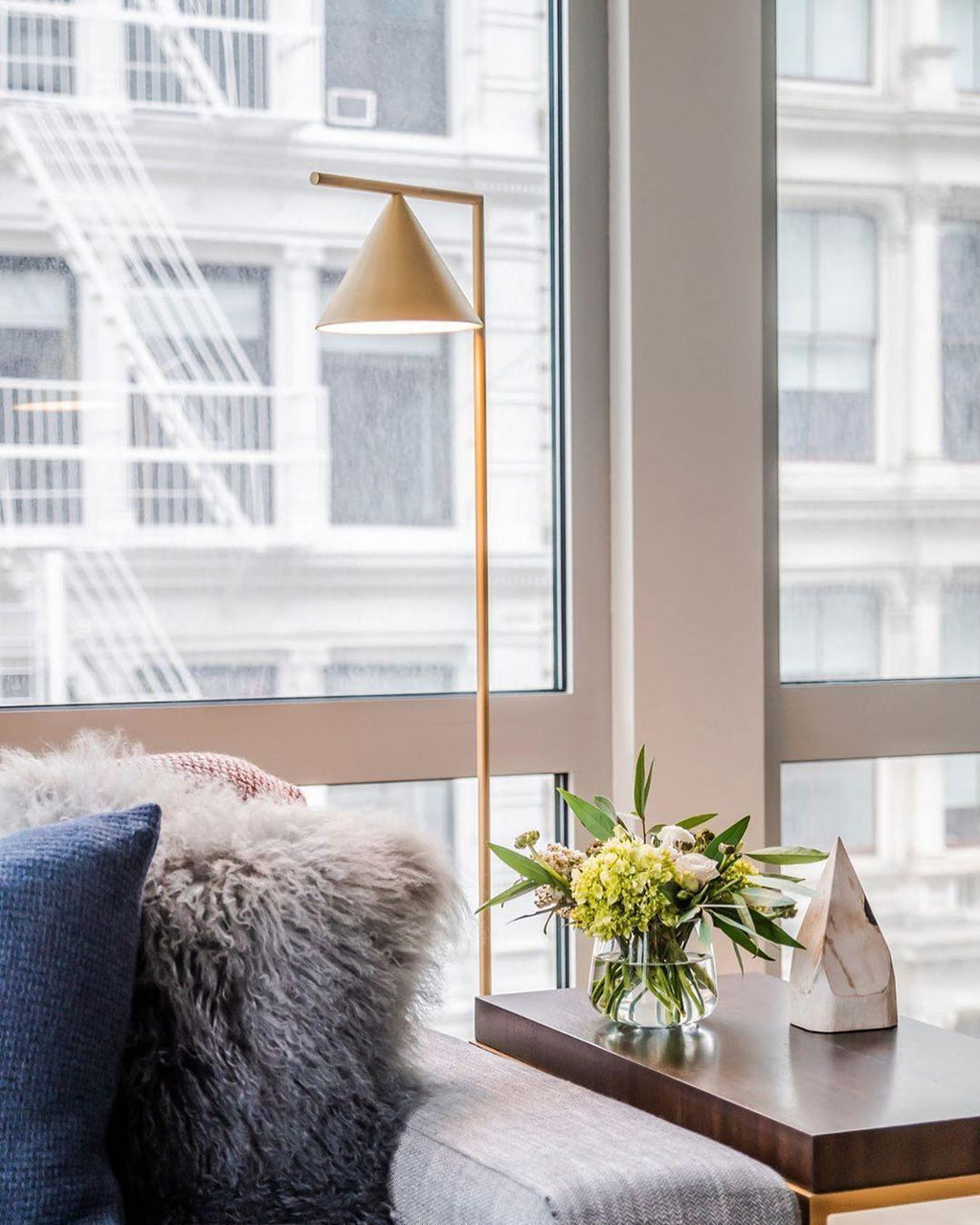 Marble-base floor lamp glowing beside a lounge chair