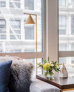 Marble-base floor lamp glowing beside a lounge chair