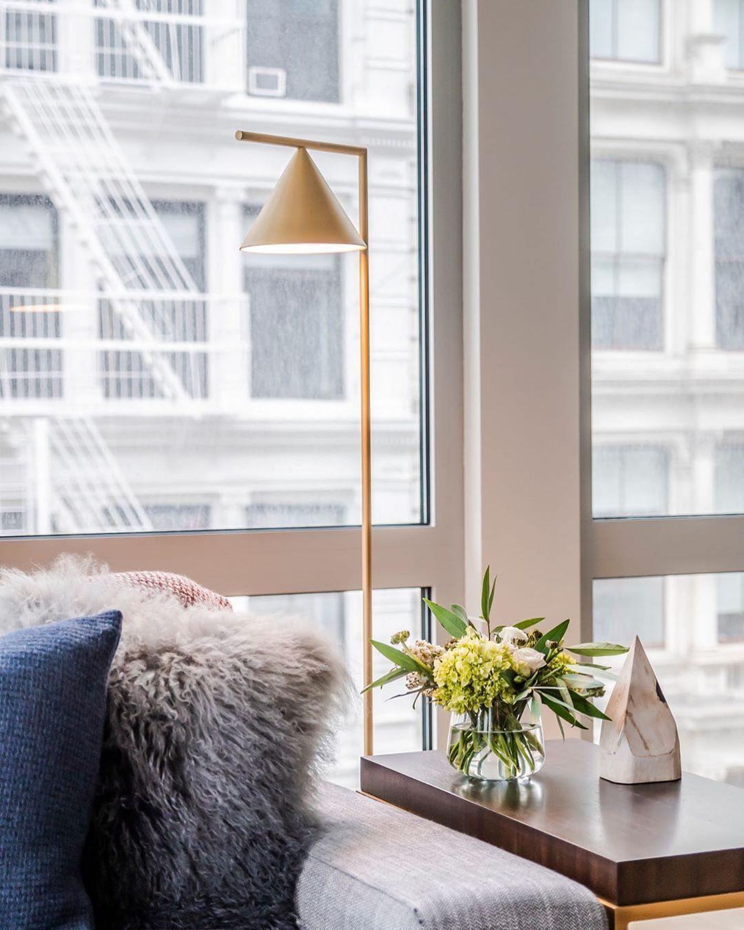 Marble-base floor lamp glowing beside a lounge chair
