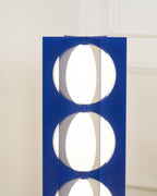 Close-up of two stacked glass globes glowing between the Clérachic floor lamp's navy metal fins.