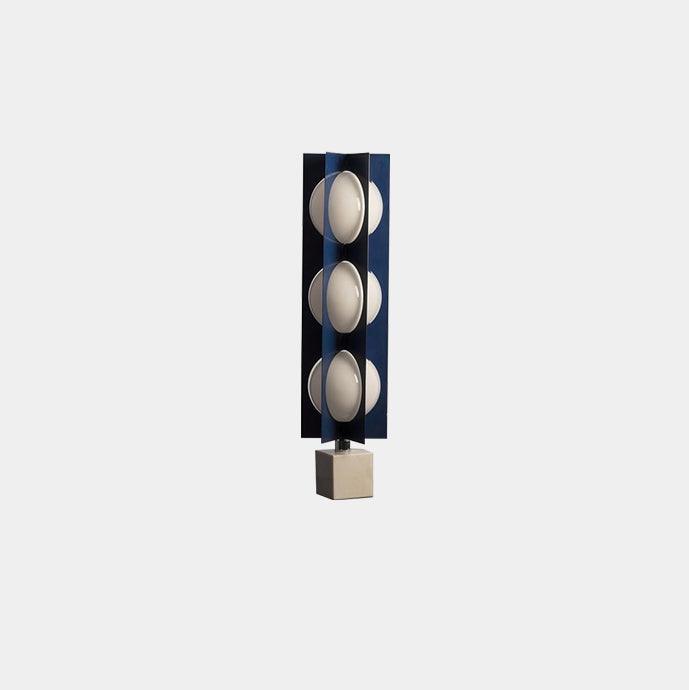 Three-globe Clérachic lamp on a warm stone base, framed slightly closer against the same plain grey backdrop.