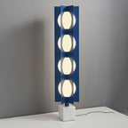 Four-globe Clérachic floor lamp on a pale square base, standing on a white surface against a plain grey wall.