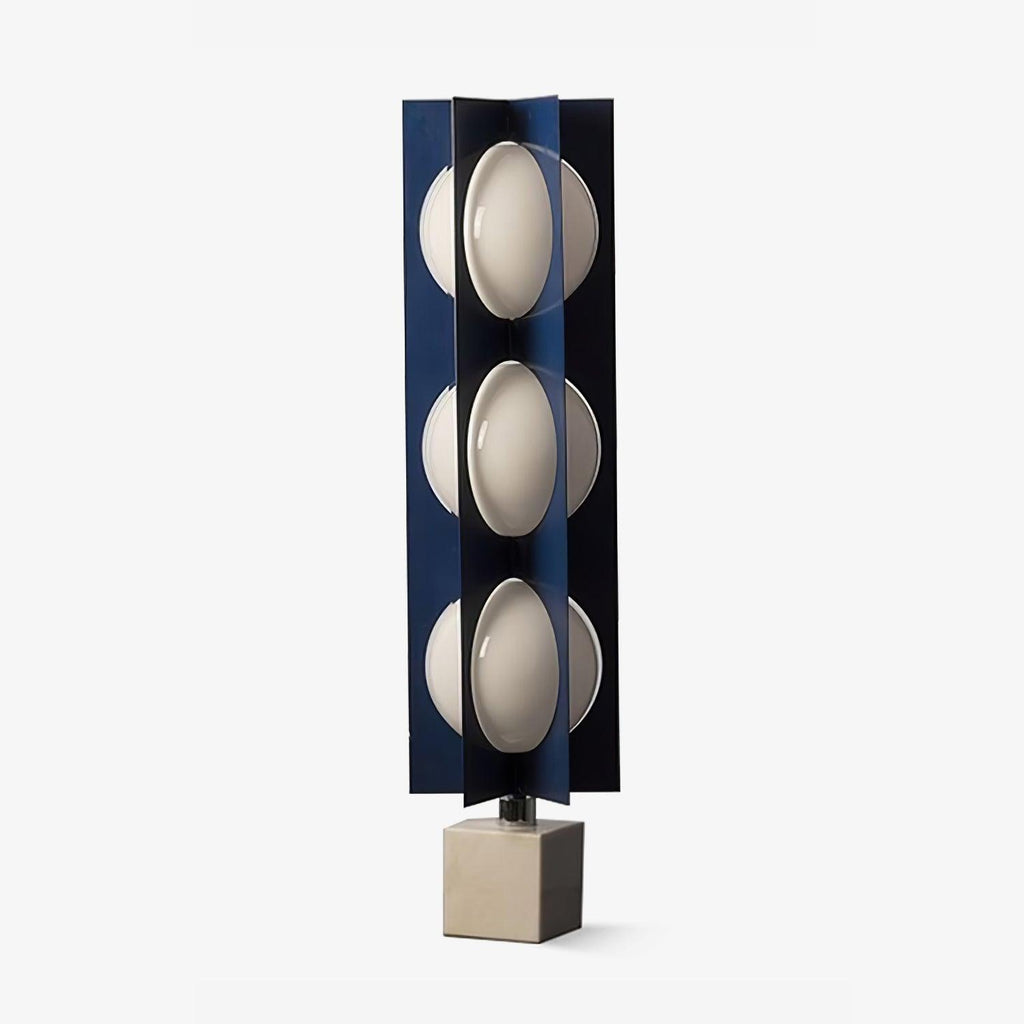 Three-globe Clérachic lamp in dark navy on a warm stone base, photographed unlit at full length in a studio set.