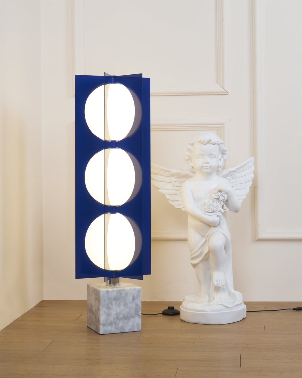 Three-globe Clérachic floor lamp on a marble base, cropped tighter to show its stacked glass globes by the statue.