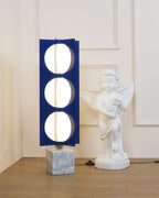 Three-globe Clérachic floor lamp on a marble base, cropped tighter to show its stacked glass globes by the statue.