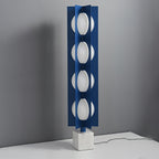 Four-globe Clérachic floor lamp on a pale base, photographed from a wider angle against a plain grey wall.