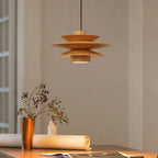 This Clérachic pendant lamp in nature wood hangs above a table with a copper vase of dried flowers and rolled papers.