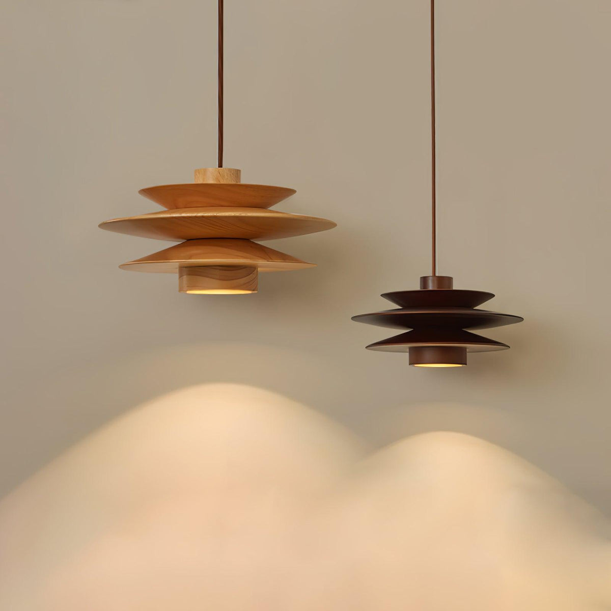 Nature wood and walnut wood versions of this Clérachic pendant lamp hang side by side, their light pooling on the floor beneath them.