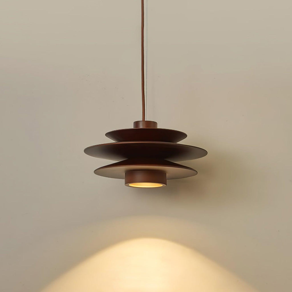 Soft light catches the tiered shade of this Clérachic pendant in walnut wood against a plain grey backdrop.