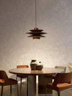 Seen from further back, this Clérachic pendant in walnut wood hangs above a round table ringed by wood and leather chairs.
