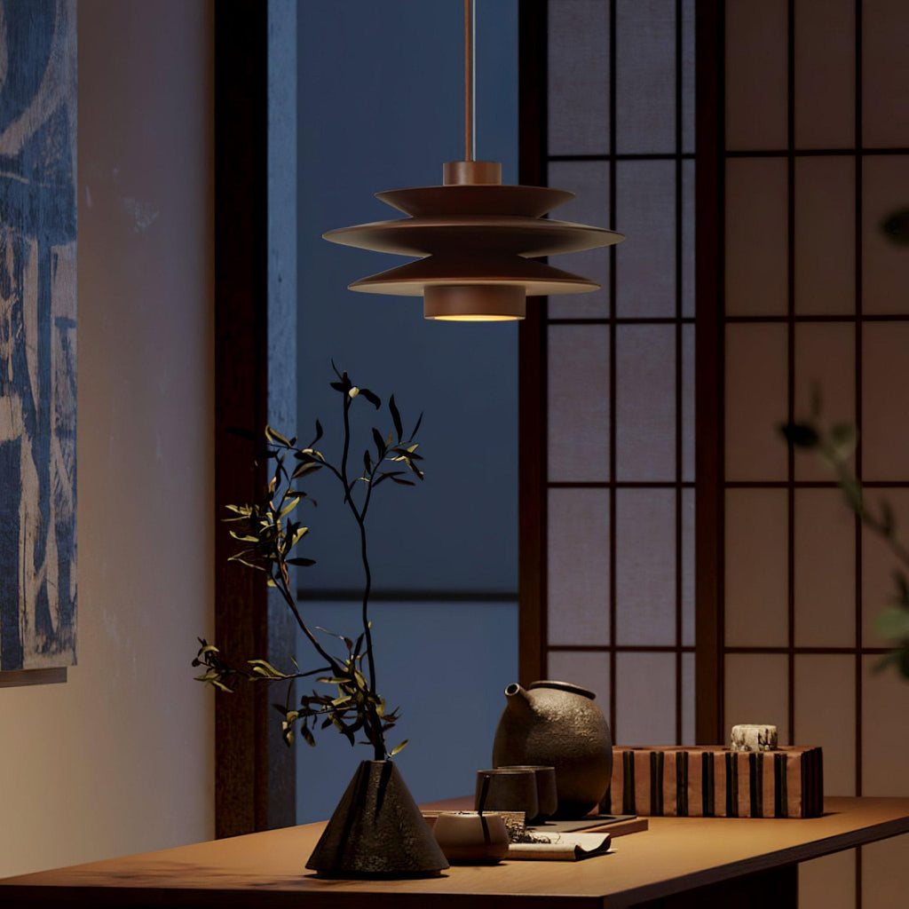 In a dim evening room, this Clérachic pendant in walnut wood hangs beside a paper screen and a dark wood table holding a branch in a vase.