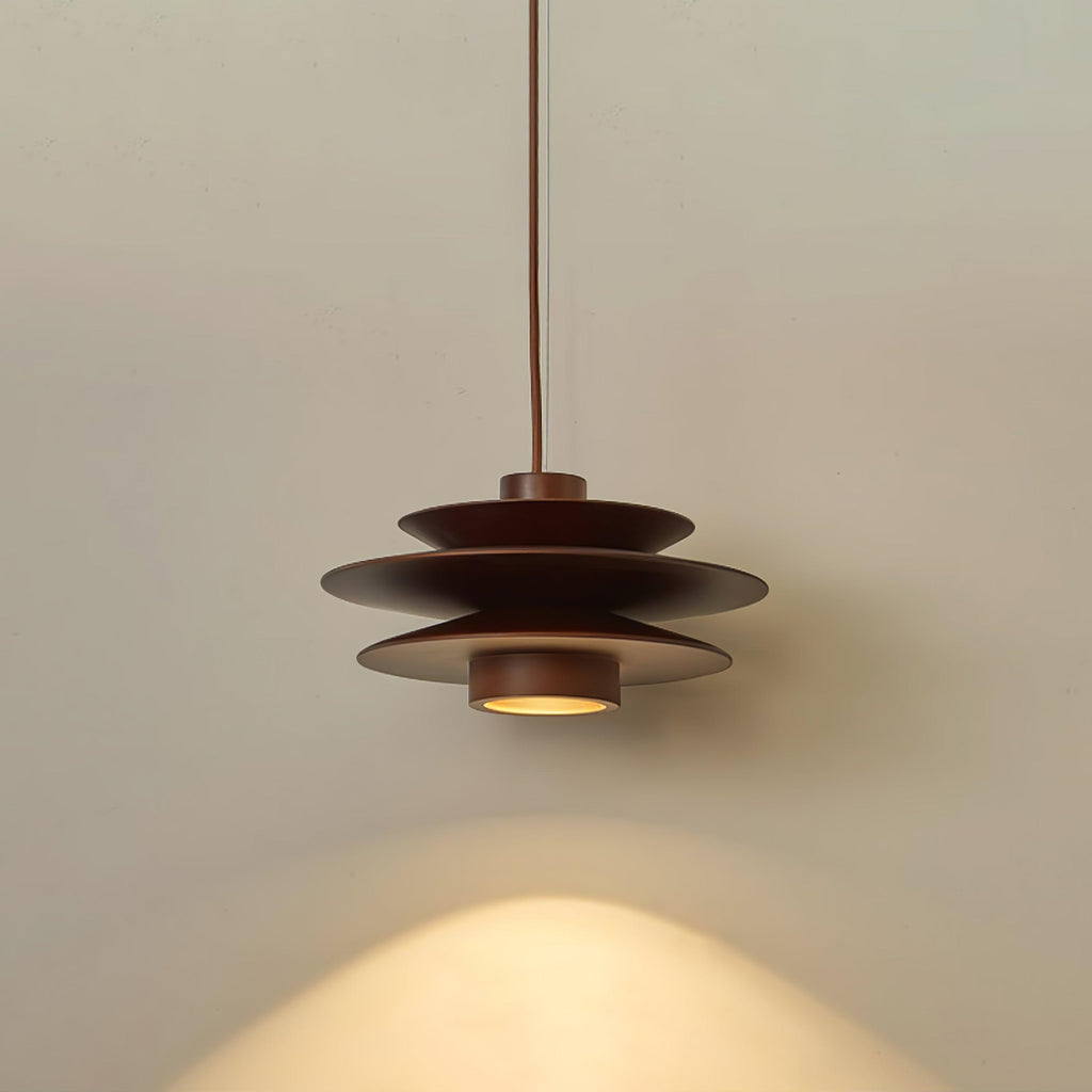 This Clérachic pendant in walnut wood hangs against a plain grey backdrop, its cord rising straight from the shade.