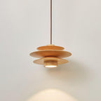 Against a plain grey backdrop, this Clérachic pendant in nature wood spreads warm light beneath its tiered discs.