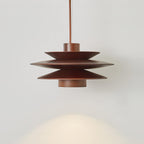 A close side view of this Clérachic pendant in walnut wood on a grey backdrop, its tiered discs glowing warm light.