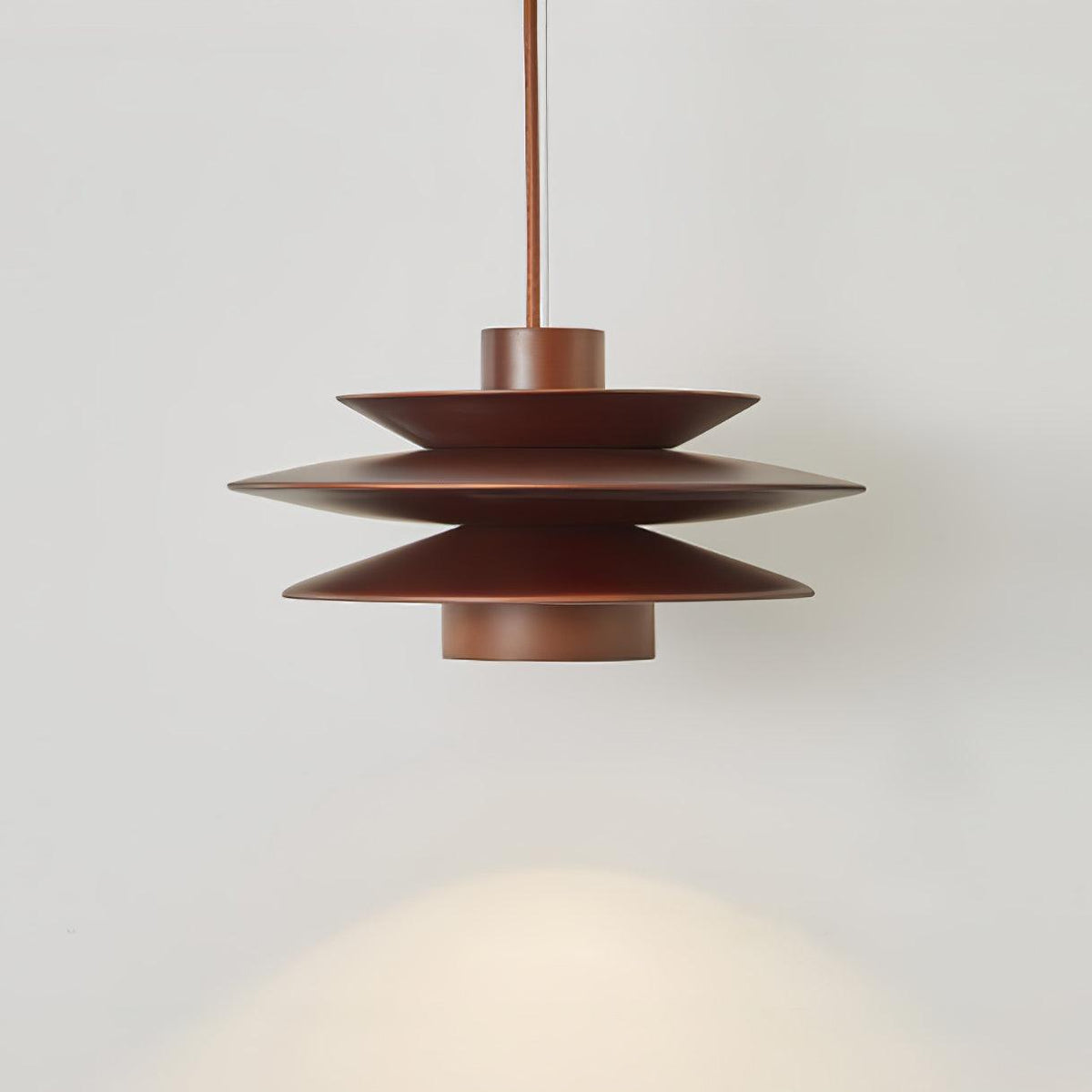 A close side view of this Clérachic pendant in walnut wood on a grey backdrop, its tiered discs glowing warm light.