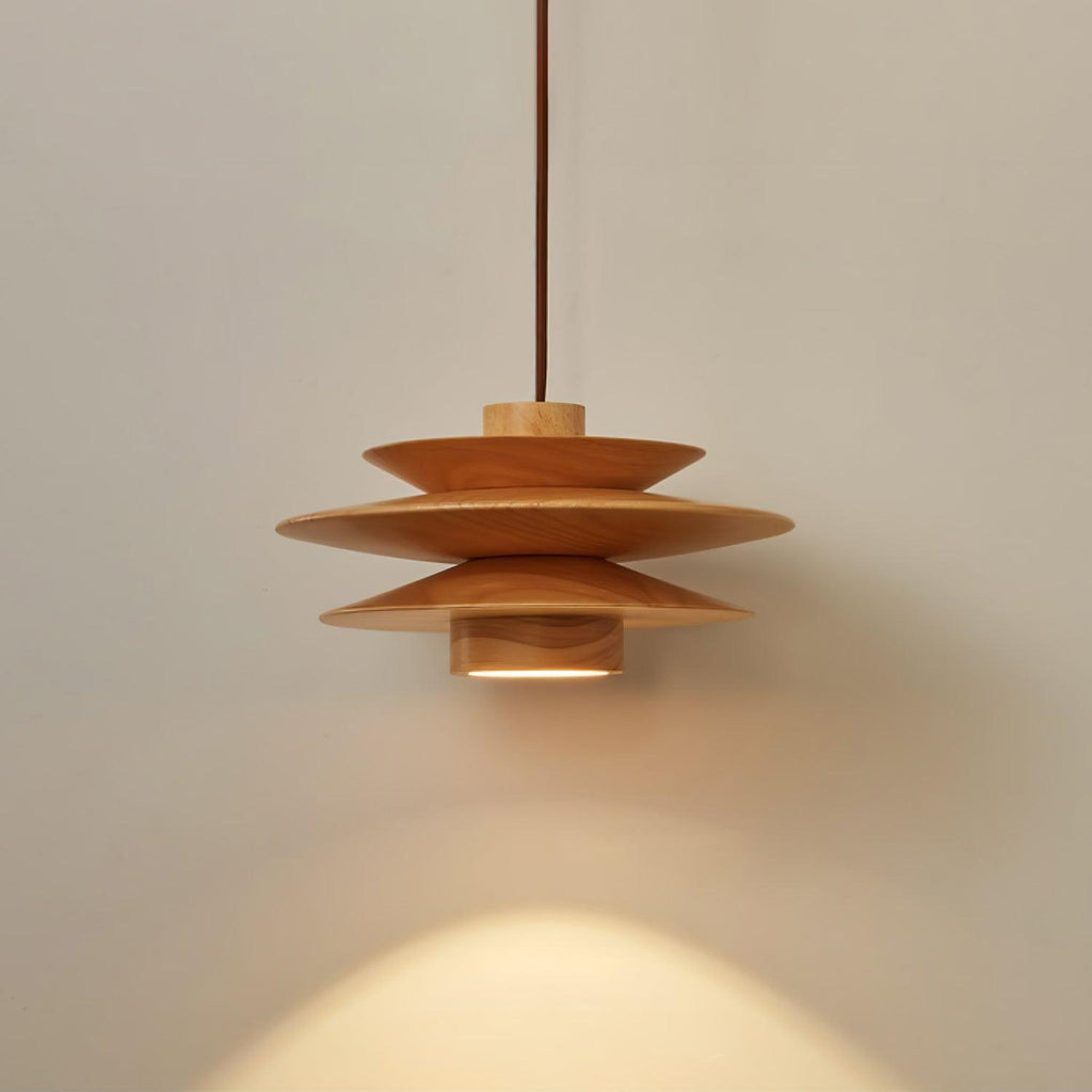 An angled view of this Clérachic pendant in nature wood shows the top disc and cord against a grey backdrop.