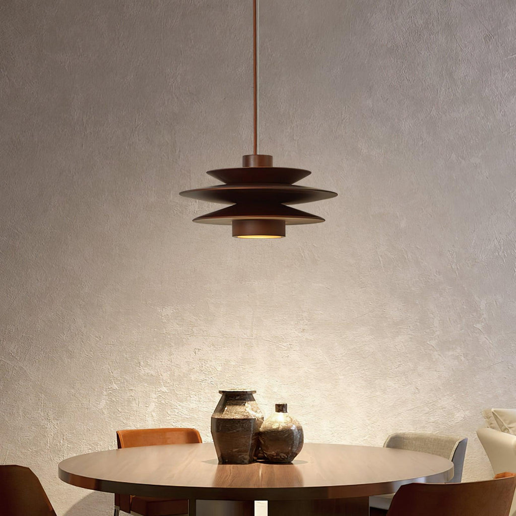 Above a round table with dark ceramic vases, this Clérachic pendant in walnut wood glows softly beneath a plaster-textured wall.