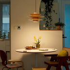Lighting a small round table with an orchid, this Clérachic pendant in nature wood brightens a teal-accented kitchen nook.