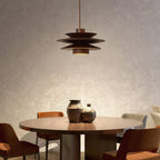 Hung low over a round dining table, this Clérachic pendant in walnut wood sits between two seating areas in a plaster-walled room.