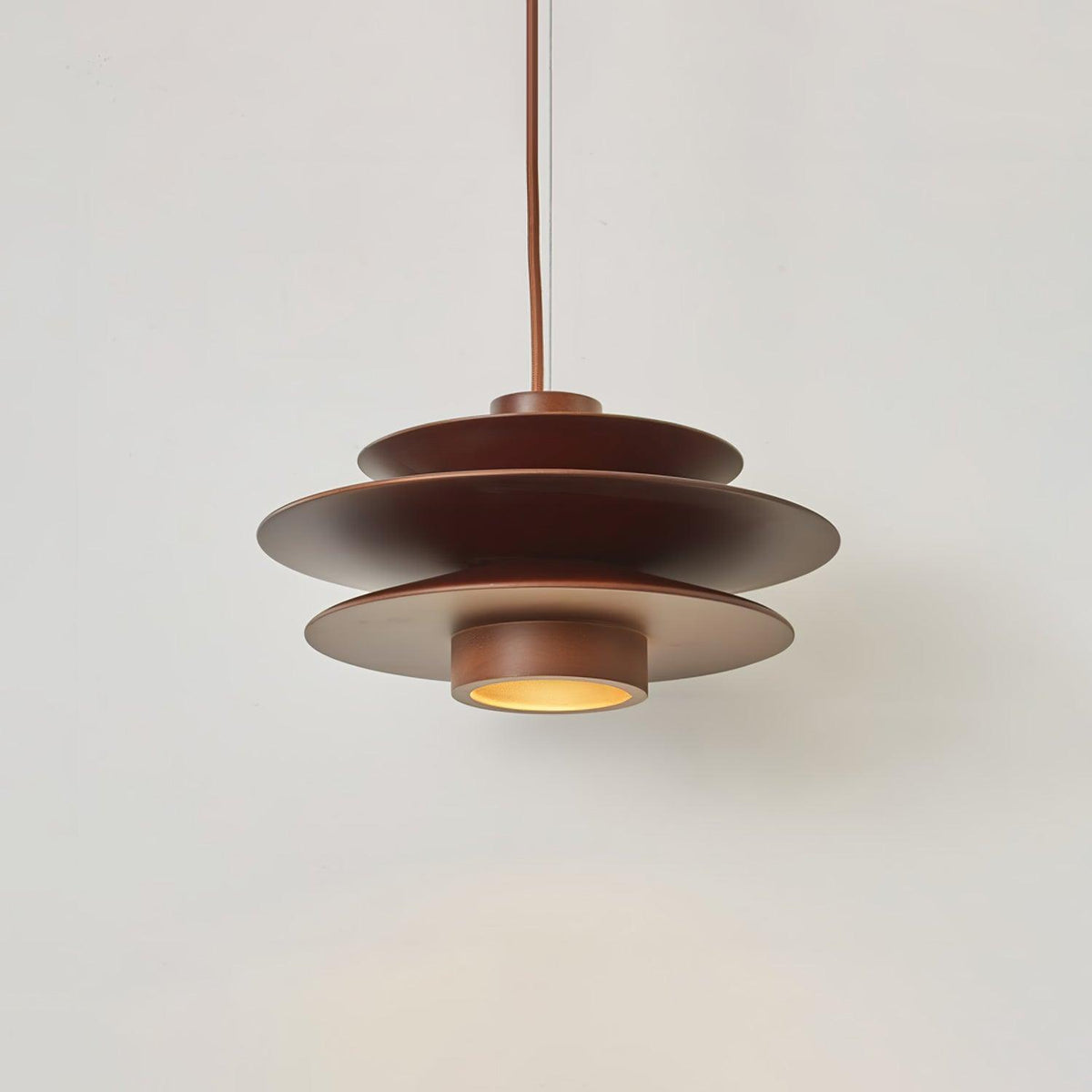 Close view of this Clérachic pendant in walnut wood, showing its stacked disc shade and the slim diffuser beneath it.