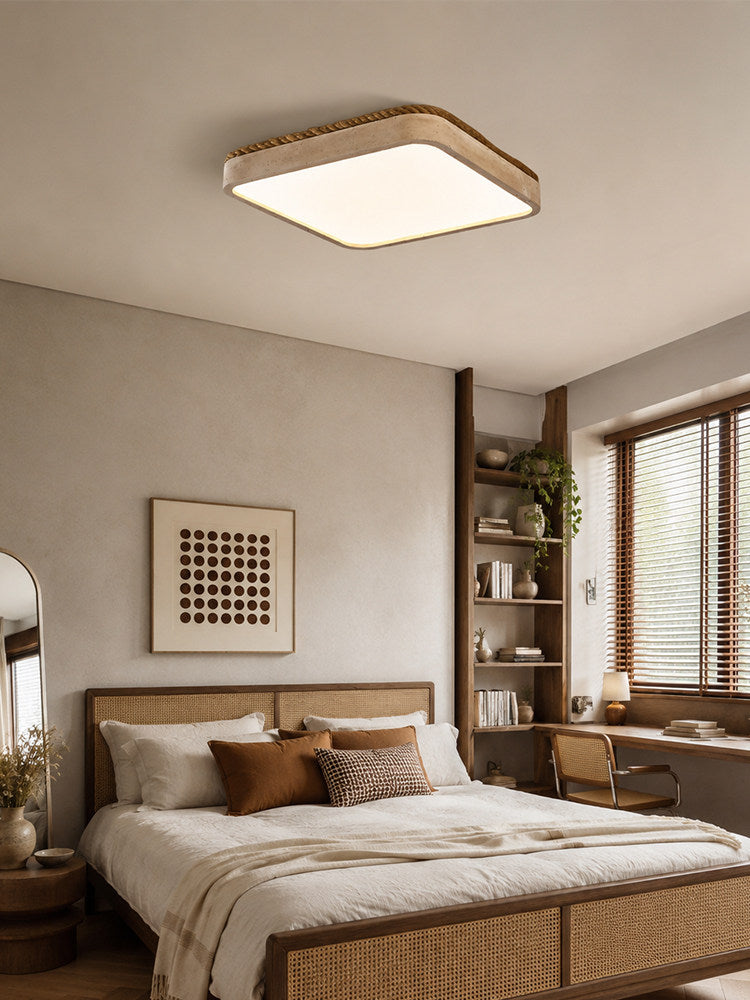 Above a bed with a woven cane headboard, this square Clérachic ceiling light glows near a round mirror and dotted wall art.