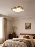 Above a bed beside a wooden chest of drawers, this square Clérachic ceiling light glows warm in a quiet bedroom corner.