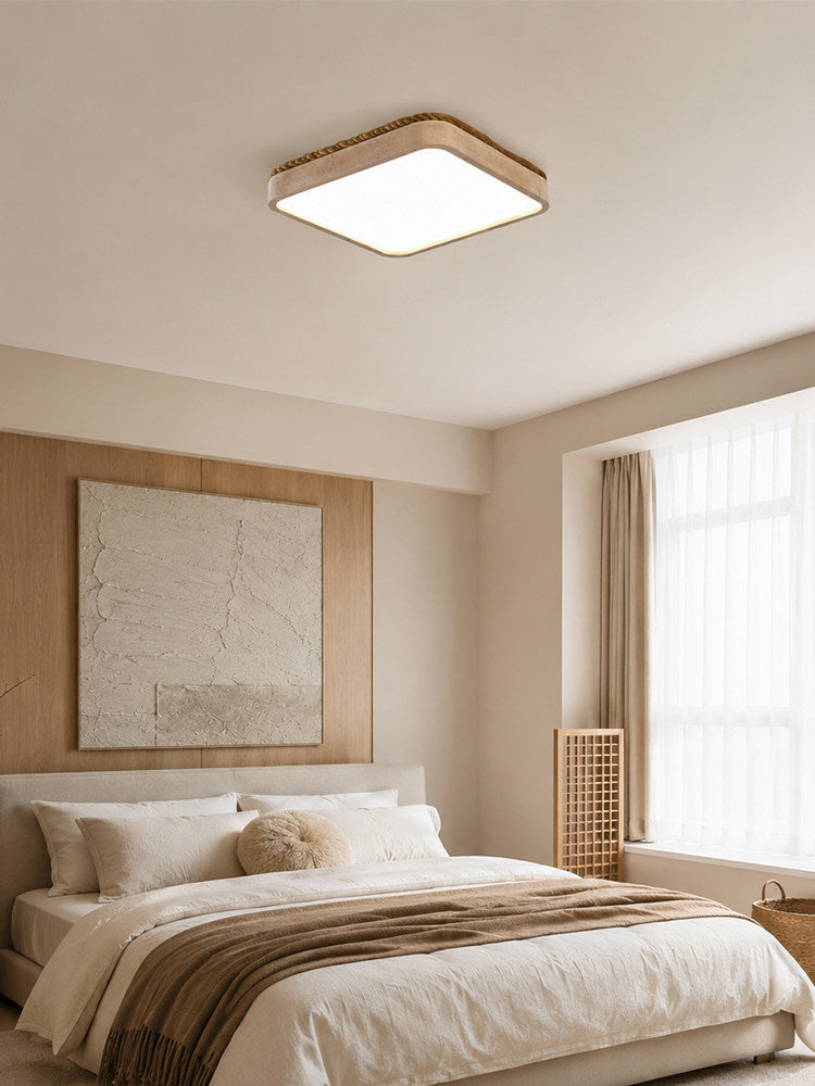 This Clérachic flush mount light glows softly above a bed set against a textured plaster wall panel.