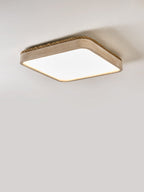 Side profile of this Clérachic flush mount light, its low travertine body and rope edge caught in soft grey light.