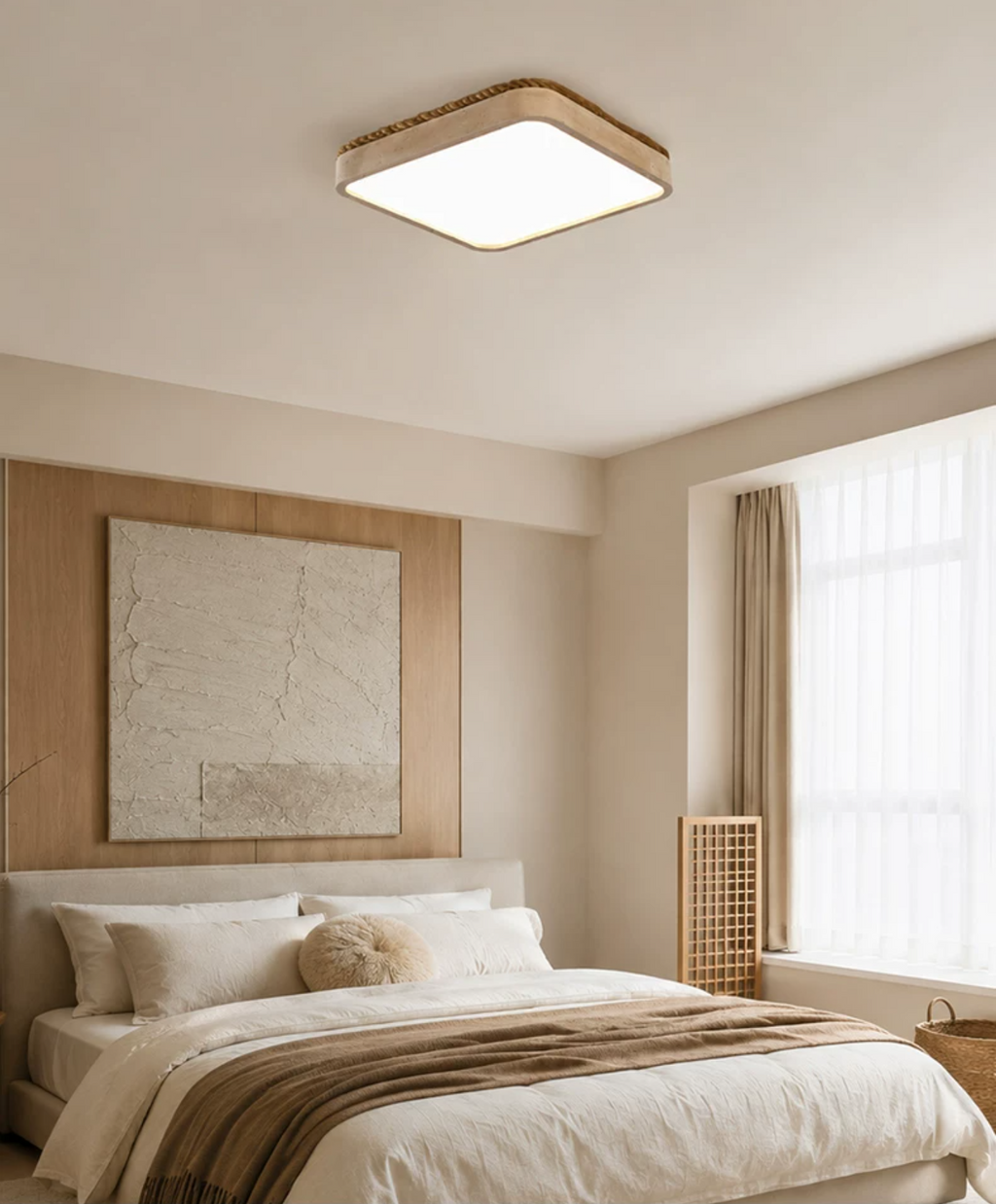 This Clérachic ceiling light glows warm above a bed dressed with a woven throw, beside a framed abstract print.