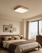 A gallery of framed prints lines the wall below this square Clérachic ceiling light, glowing warm above a dressed bed.