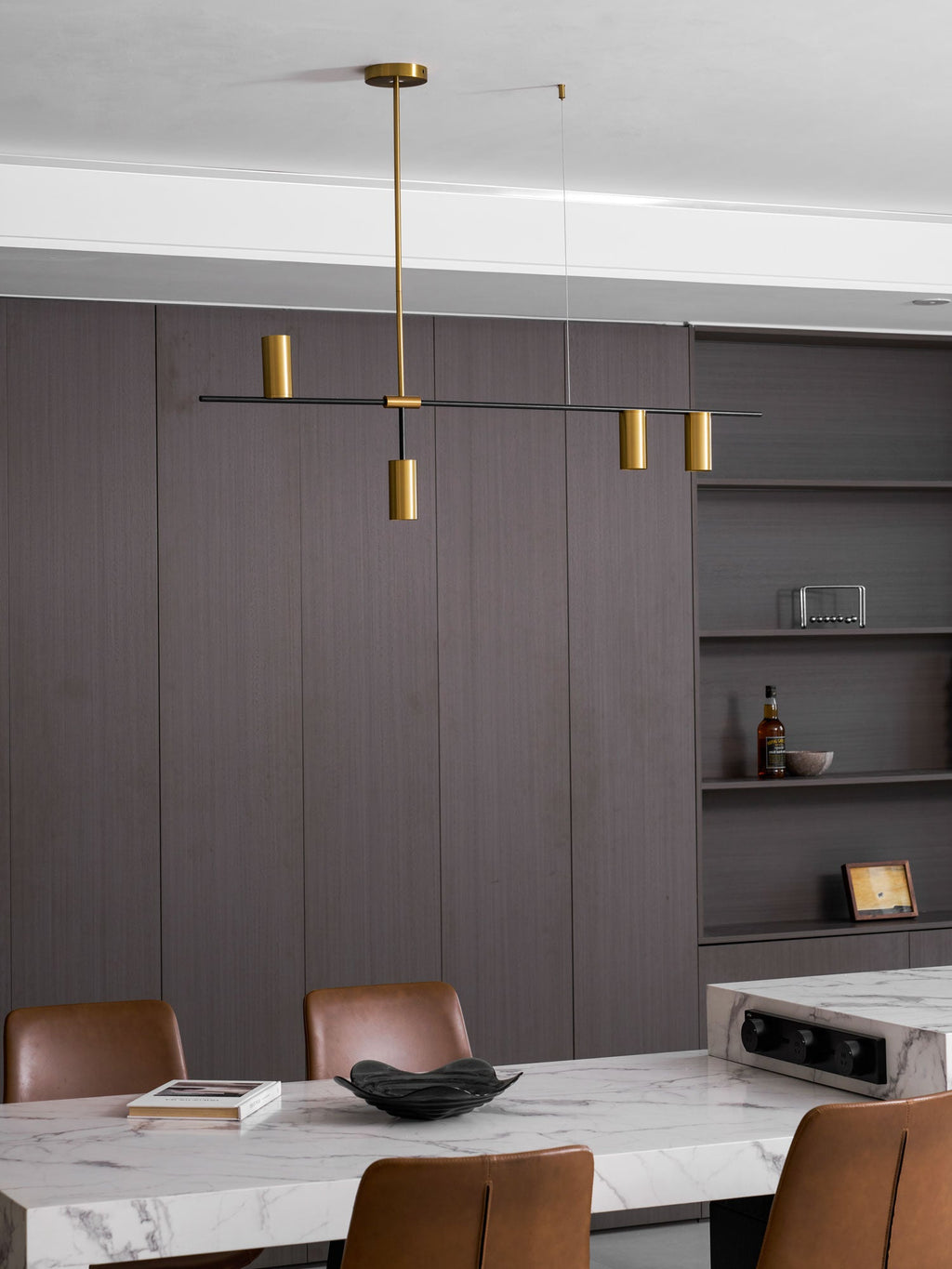 In a warm brown panelled dining room, this Clérachic chandelier hangs above a marble-topped table.