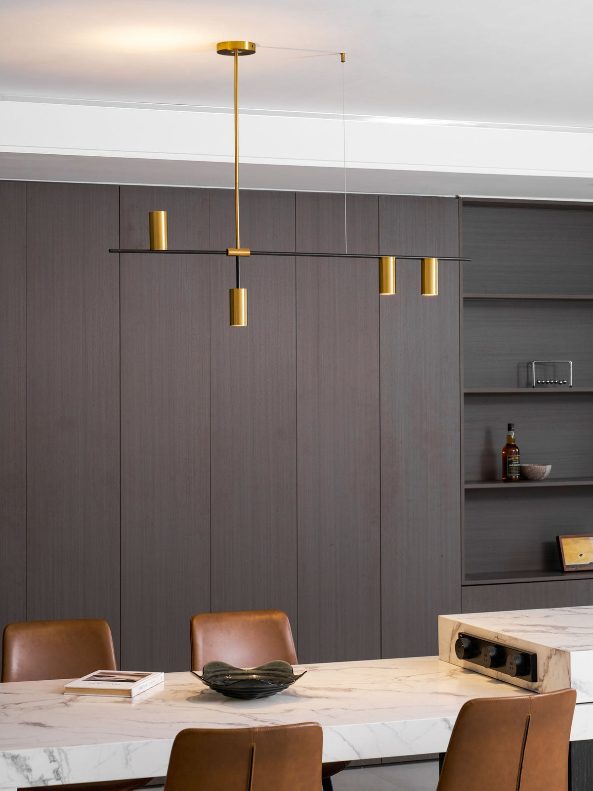 This Clérachic chandelier glows softly above a marble table, its gold heads set against brown wall panelling.