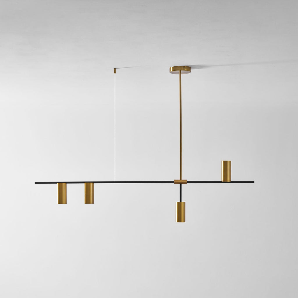 On a plain light-grey background, this Clérachic chandelier's black bar holds gold cylinder heads at staggered heights.