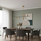 Beneath a sage-green wall and abstract artwork, this Clérachic chandelier hangs above a walnut dining table.