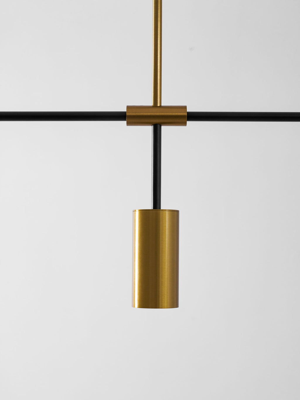 Close view of the central mount on this Clérachic chandelier, where a gold cylinder head hangs below the black crossbar.