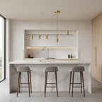 This Clérachic chandelier's black bar and brushed gold cylinder heads hang above a marble kitchen island with three tan stools.