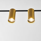 Close view of two brushed gold spotlight heads on this Clérachic chandelier's black bar, each showing its bulb.