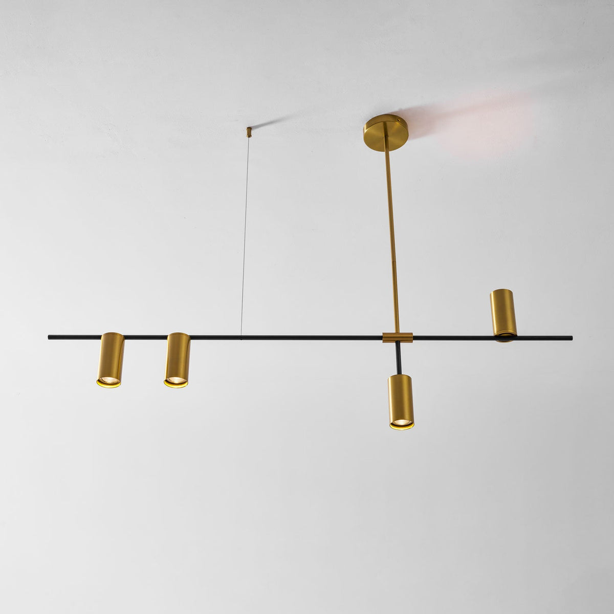 On a plain white background, this Clérachic chandelier's gold ceiling rod meets a black bar fitted with cylinder heads.