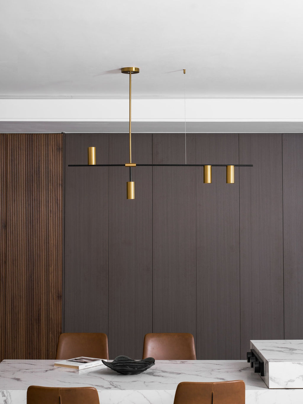 In a dark panelled dining nook, this Clérachic chandelier hangs above a marble table and tan leather chairs.