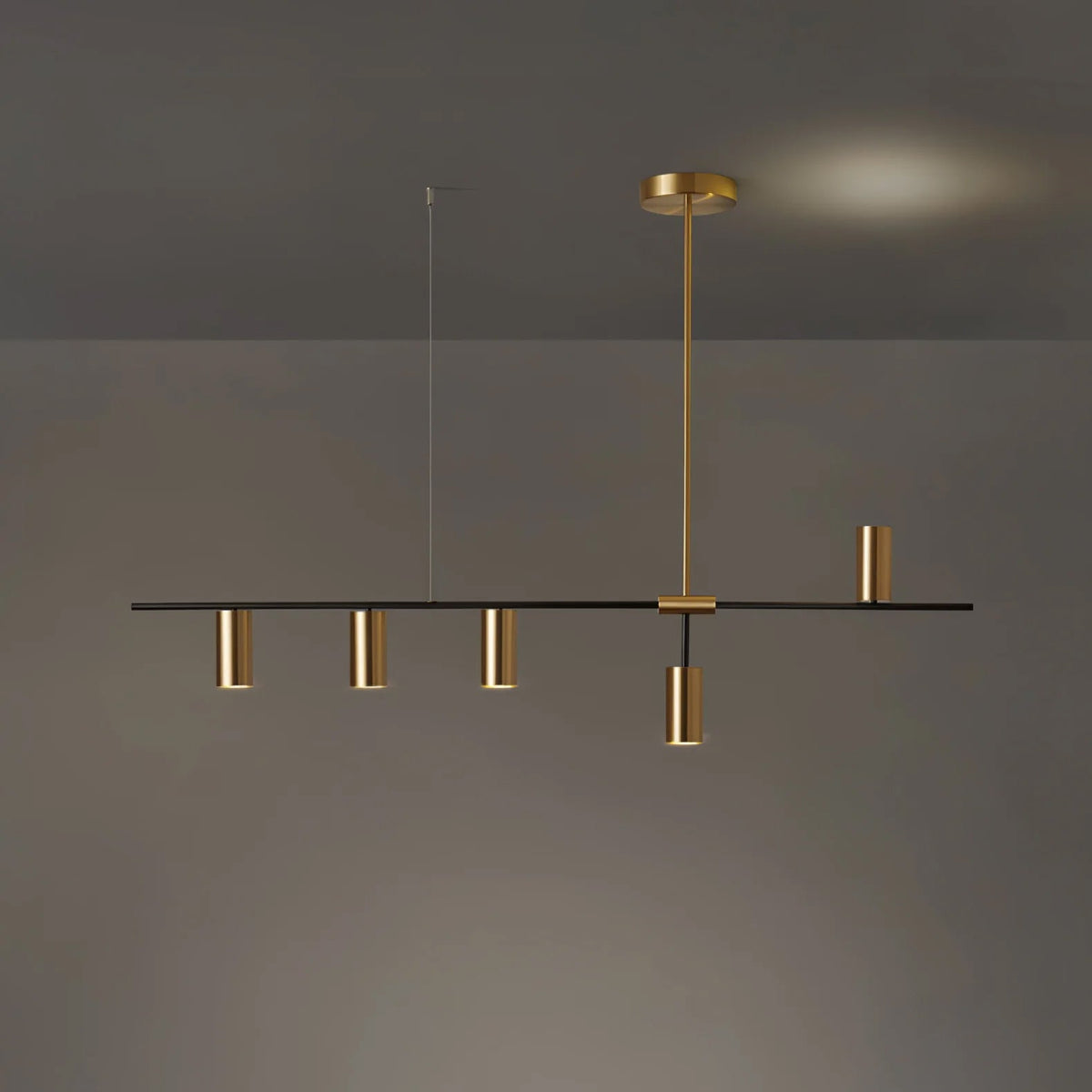 In the gold finish, this Clérachic chandelier's rod and cylinder heads match, seen against a dim backdrop with a warm glow.