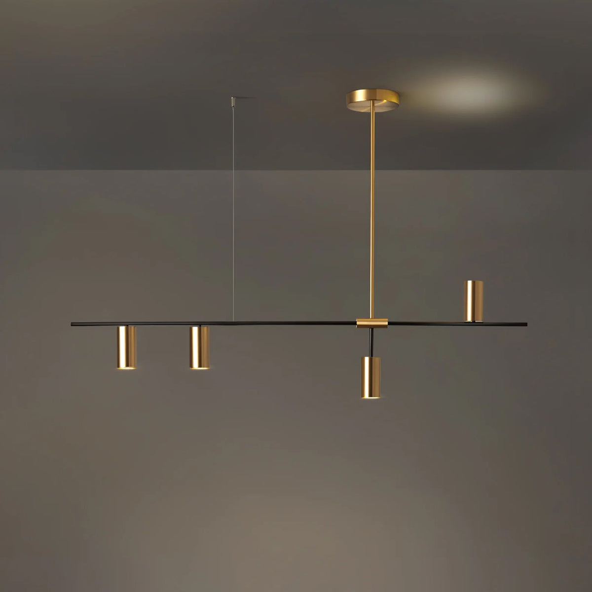 Against a dim grey backdrop with a warm glow behind, this Clérachic chandelier hangs with gold heads clustered near centre.