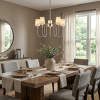 This nickel Clérachic chandelier hangs above a table set with grey chairs and sheer curtains.