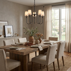 This black Clérachic chandelier hangs above a rustic wood table with beige upholstered dining chairs.