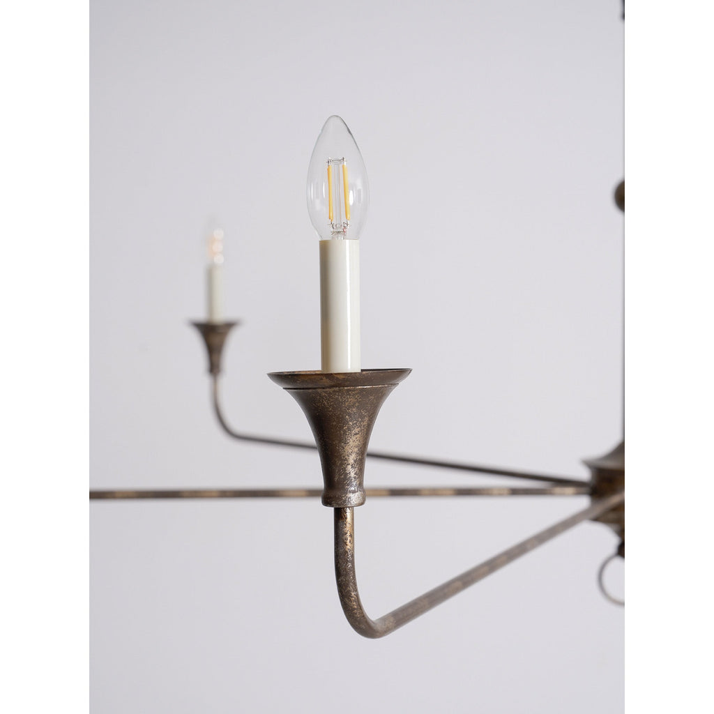 Candle chandelier finish detail on a curved brass arm